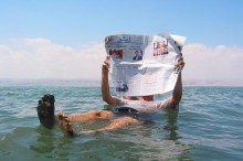 Man reading a newspaper in the Dead Sea.
