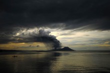 As a fisherman waits patiently for the fish to bite, Tavurvur belches ash and pumice into the twilight. Photo by Taro Taylor.