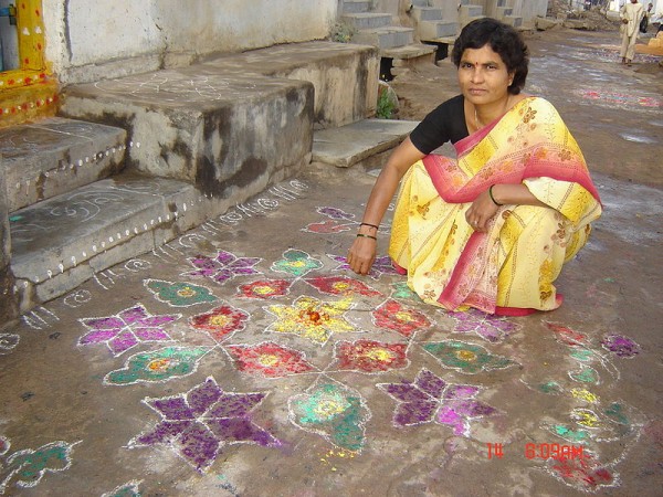 A woman drawing Muggu (coloured patterns) in front of their home during the Sankranthi Festival. Photo by  Mr. Chidambar Rao Bhukya.